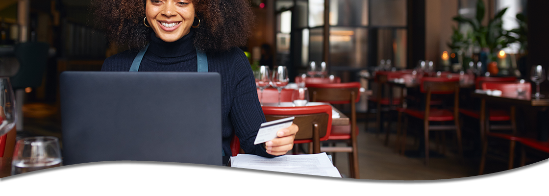 woman at a computer at a restaurant with credit card