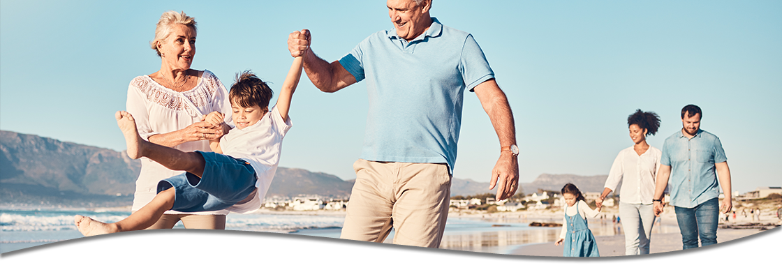 Family playing on beach, parents swinging child between them.