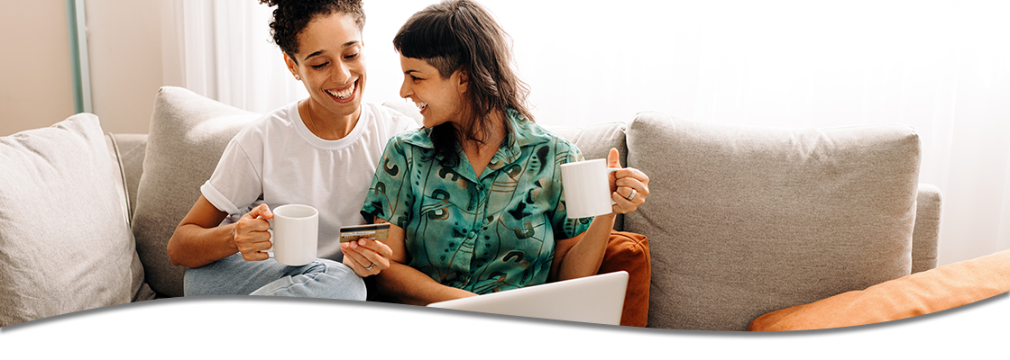 Couple on couch looking at debit card and laptop