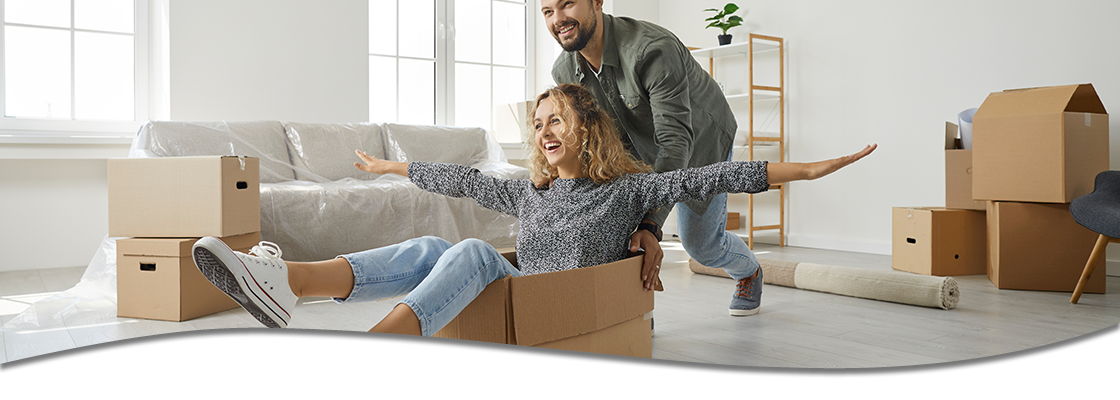 Couple moving into house, man pushing woman in a box playfully