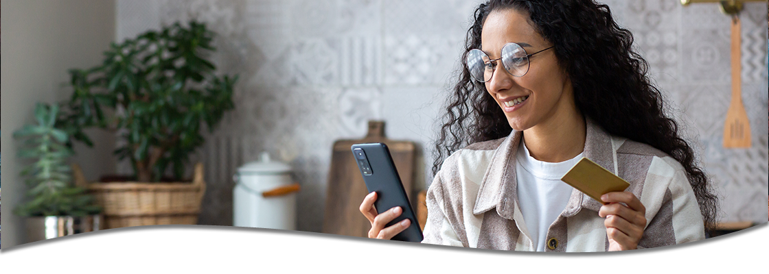 Woman using phone with card in hand