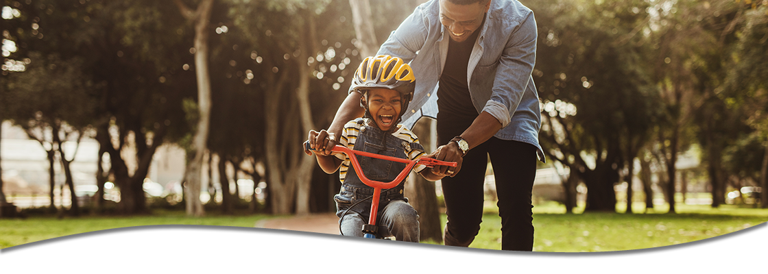 Father helping child learn to ride their bicycle